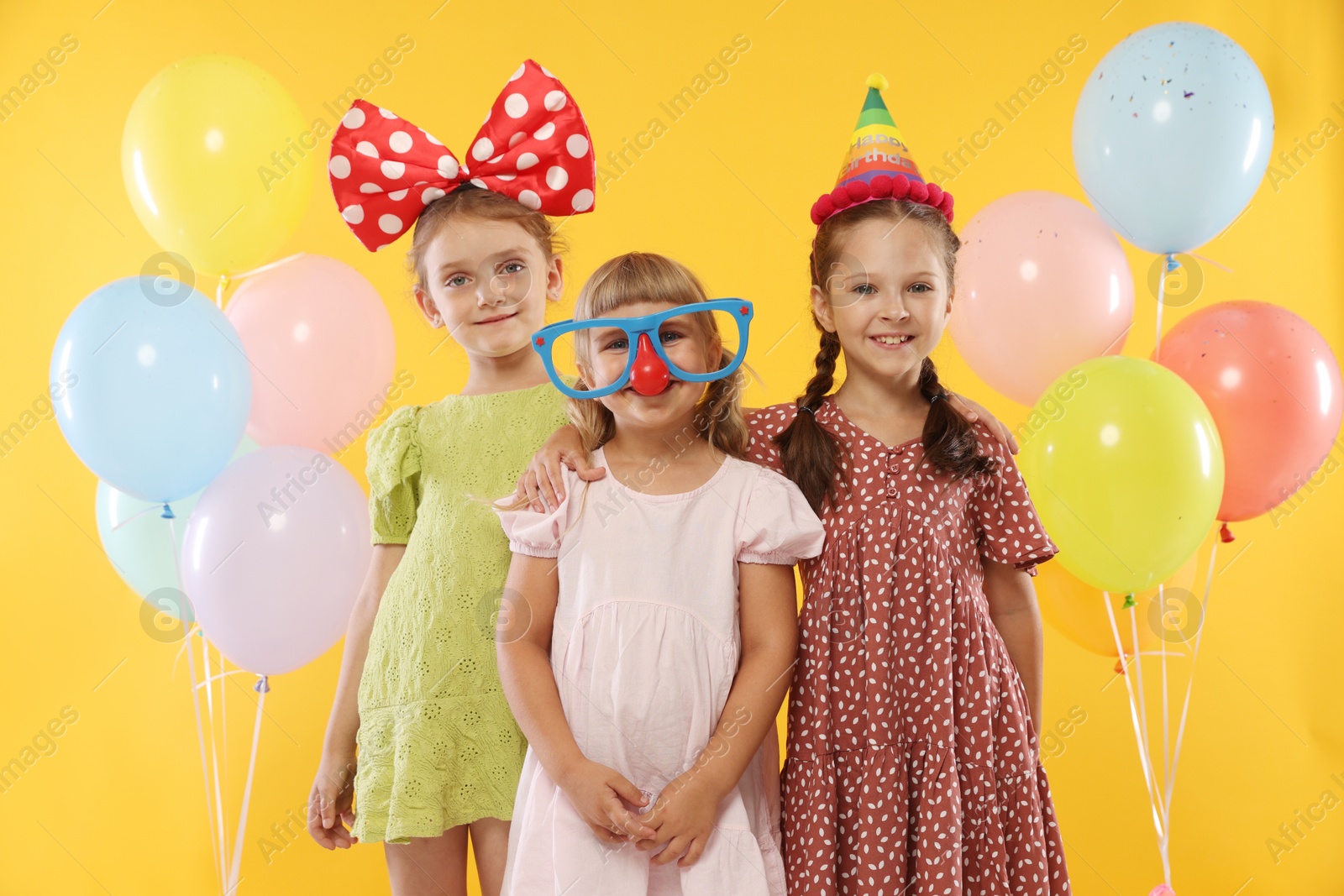 Birthday celebration. Kids with cupcake and balloons on orange background Photo of Birthday celebration. Kids with cupcake and balloons on orange background