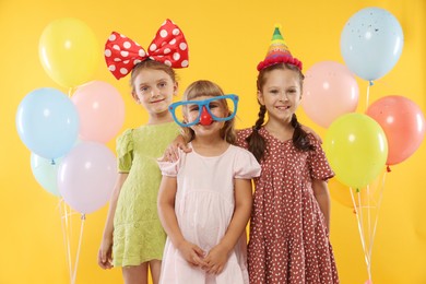 Photo of Birthday celebration. Kids with cupcake and balloons on orange background