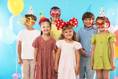 Photo of Birthday celebration. Happy kids with festive decor under falling confetti on light blue background