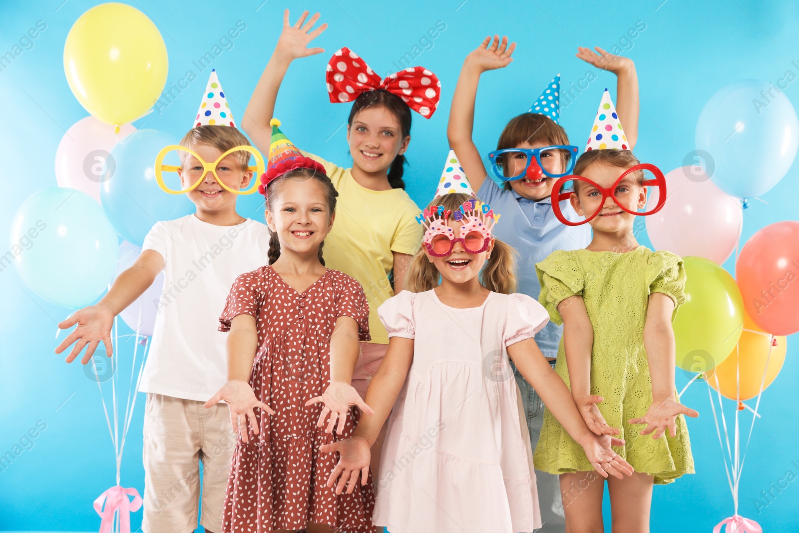 Birthday celebration. Happy kids with festive decor on light blue background Photo of Birthday celebration. Happy kids with festive decor on light blue background