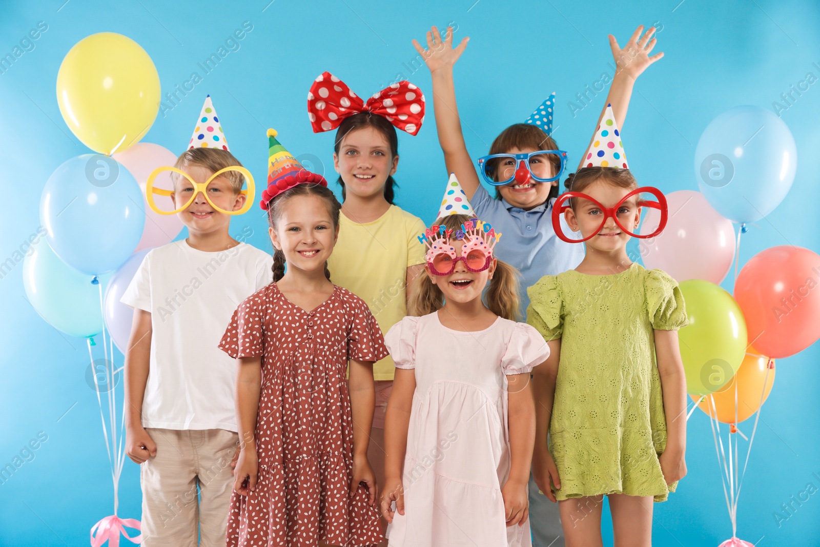Birthday celebration. Happy kids with festive decor on light blue background Photo of Birthday celebration. Happy kids with festive decor on light blue background