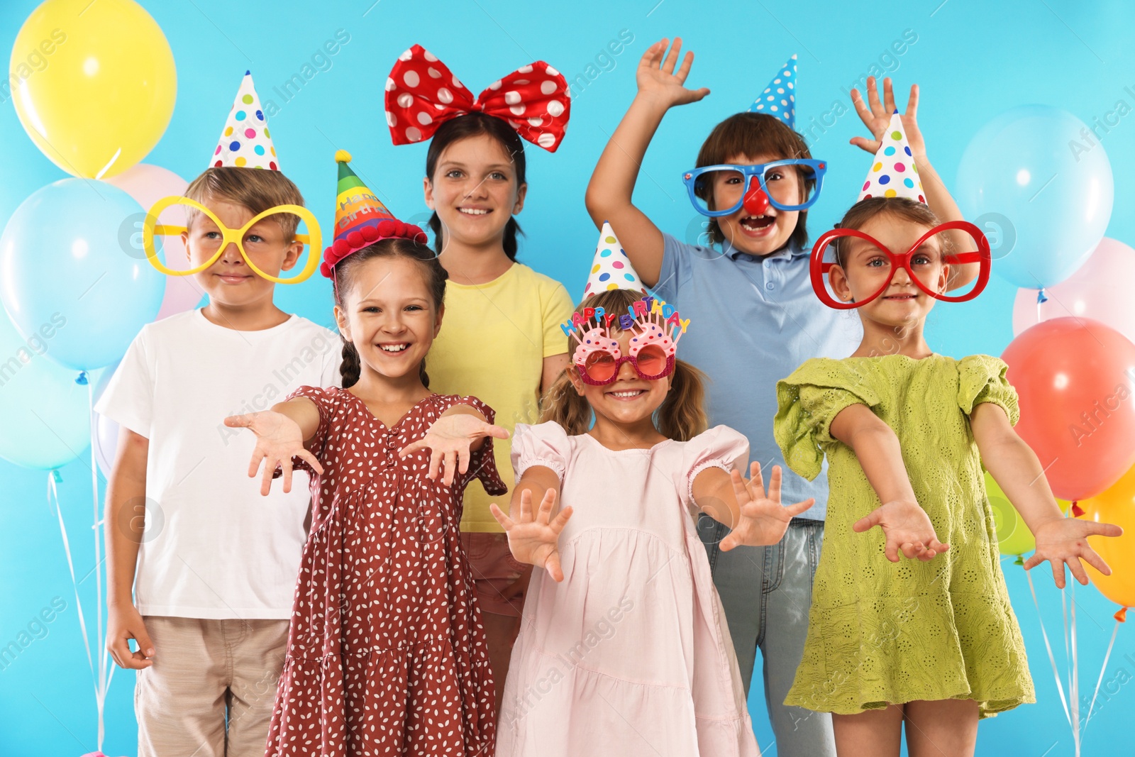 Birthday celebration. Happy kids with festive decor on light blue background Photo of Birthday celebration. Happy kids with festive decor on light blue background