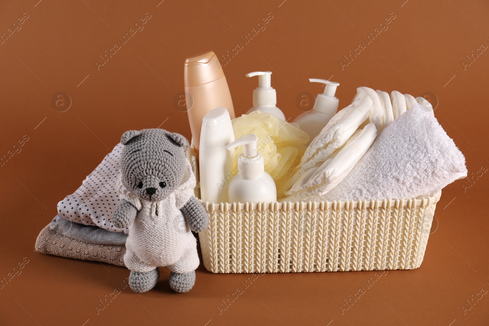 Photo of Baby accessories, clothes and body care products on brown background