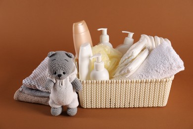 Photo of Baby accessories, clothes and body care products on brown background
