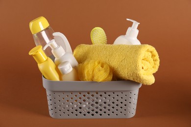 Photo of Baby accessories and body care products in basket on brown background