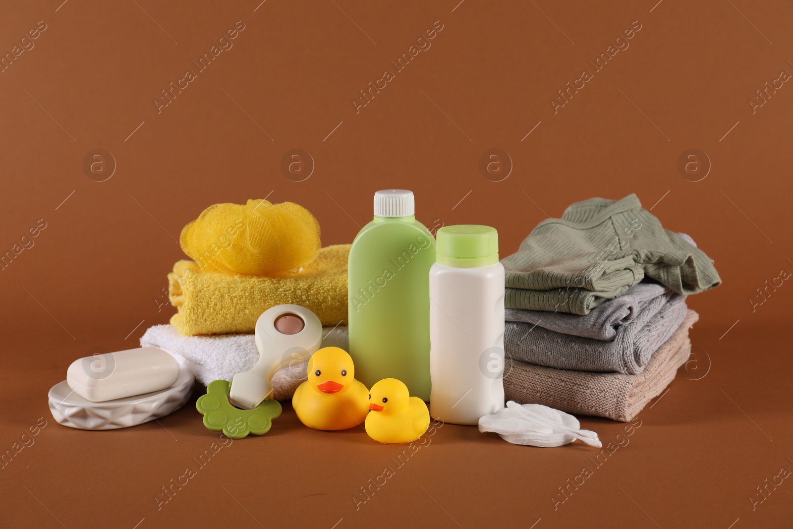 Photo of Baby accessories, clothes and body care products on brown background