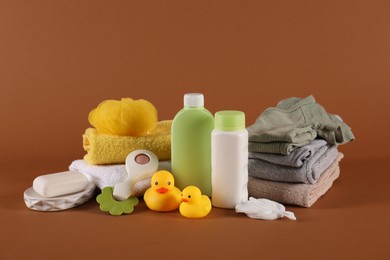 Photo of Baby accessories, clothes and body care products on brown background