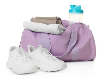 Photo of Stylish sports bag with shaker cup, clothes and sneakers isolated on white