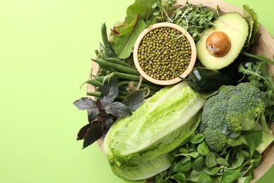 Photo of Superfood. Healthy food products in bowl on green background, top view. Space for text