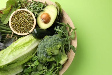Photo of Superfood. Healthy food products in bowl on green background, top view. Space for text