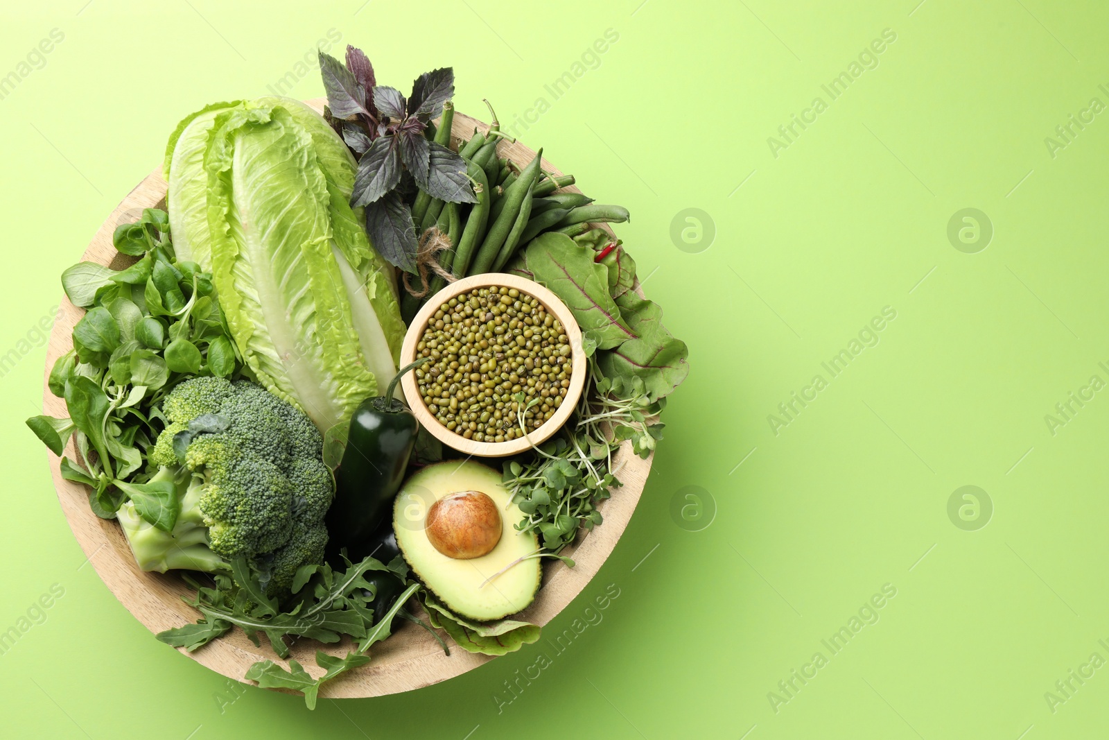 Photo of Superfood. Healthy food products in bowl on green background, top view. Space for text