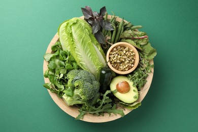 Photo of Superfood. Healthy food products in bowl on green background, top view