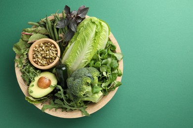 Photo of Superfood. Healthy food products in bowl on green background, top view. Space for text