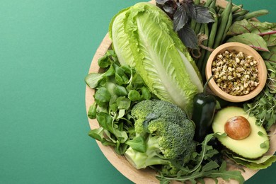 Photo of Superfood. Healthy food products in bowl on green background, top view. Space for text