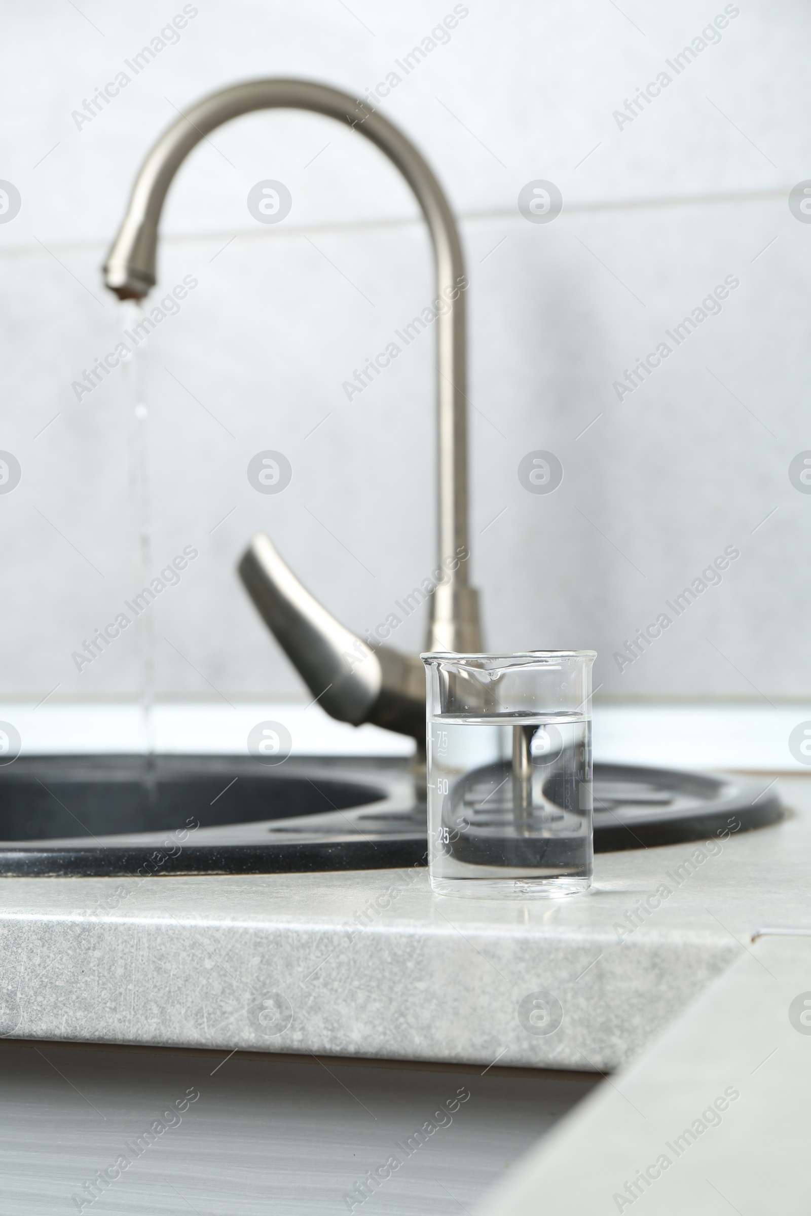 Photo of Beaker with clean water near sink on counter in kitchen, closeup