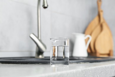 Photo of Beaker with clean water near sink on counter in kitchen, closeup