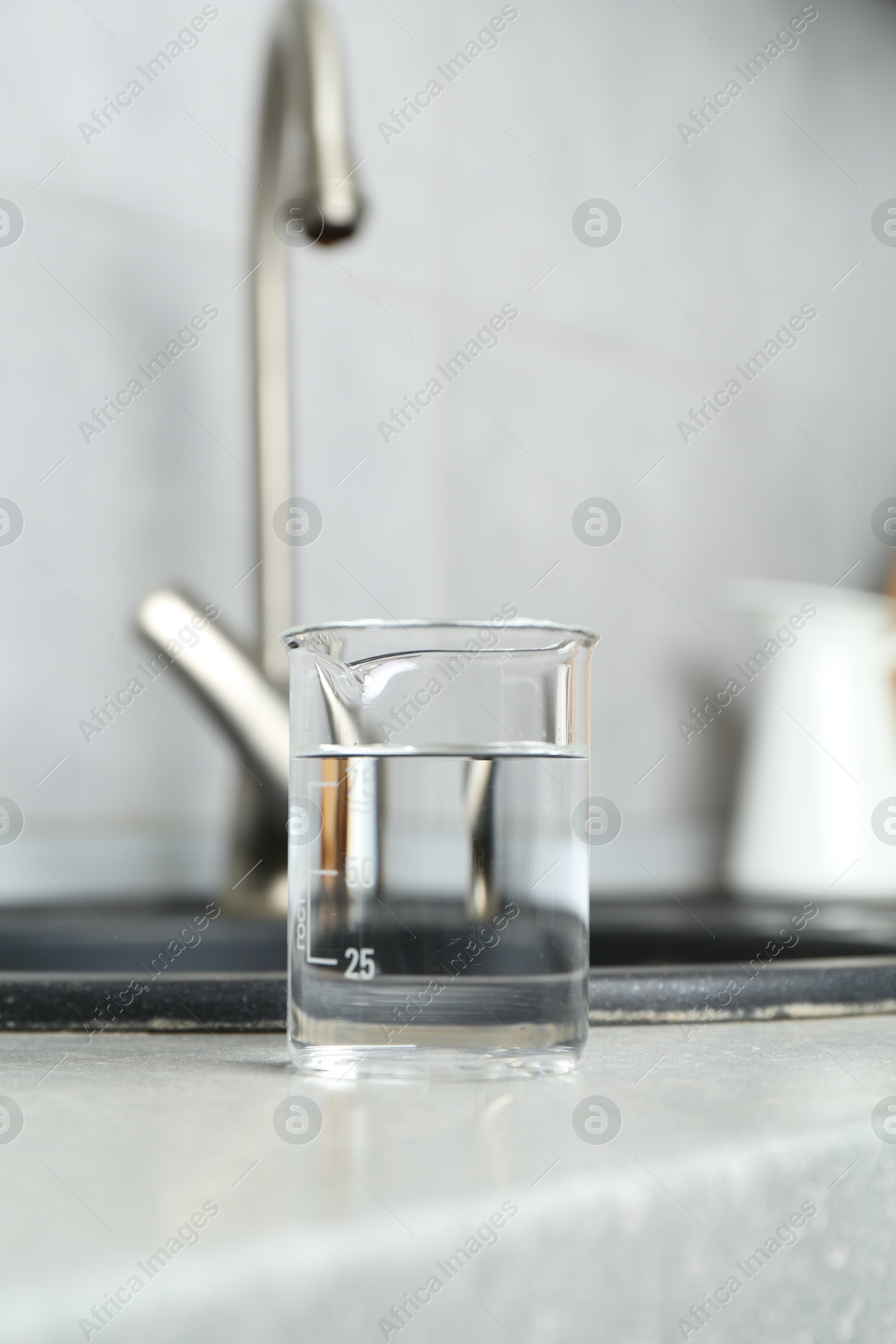 Photo of Beaker with clean water near sink on counter in kitchen, closeup