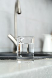 Photo of Beaker with clean water near sink on counter in kitchen, closeup