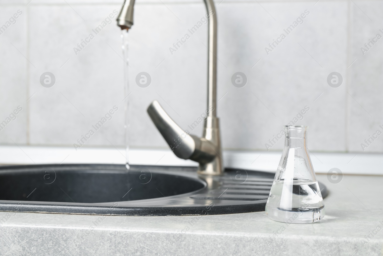 Flask with clean water near sink on counter in kitchen, closeup. Space for text Photo of Flask with clean water near sink on counter in kitchen, closeup. Space for text