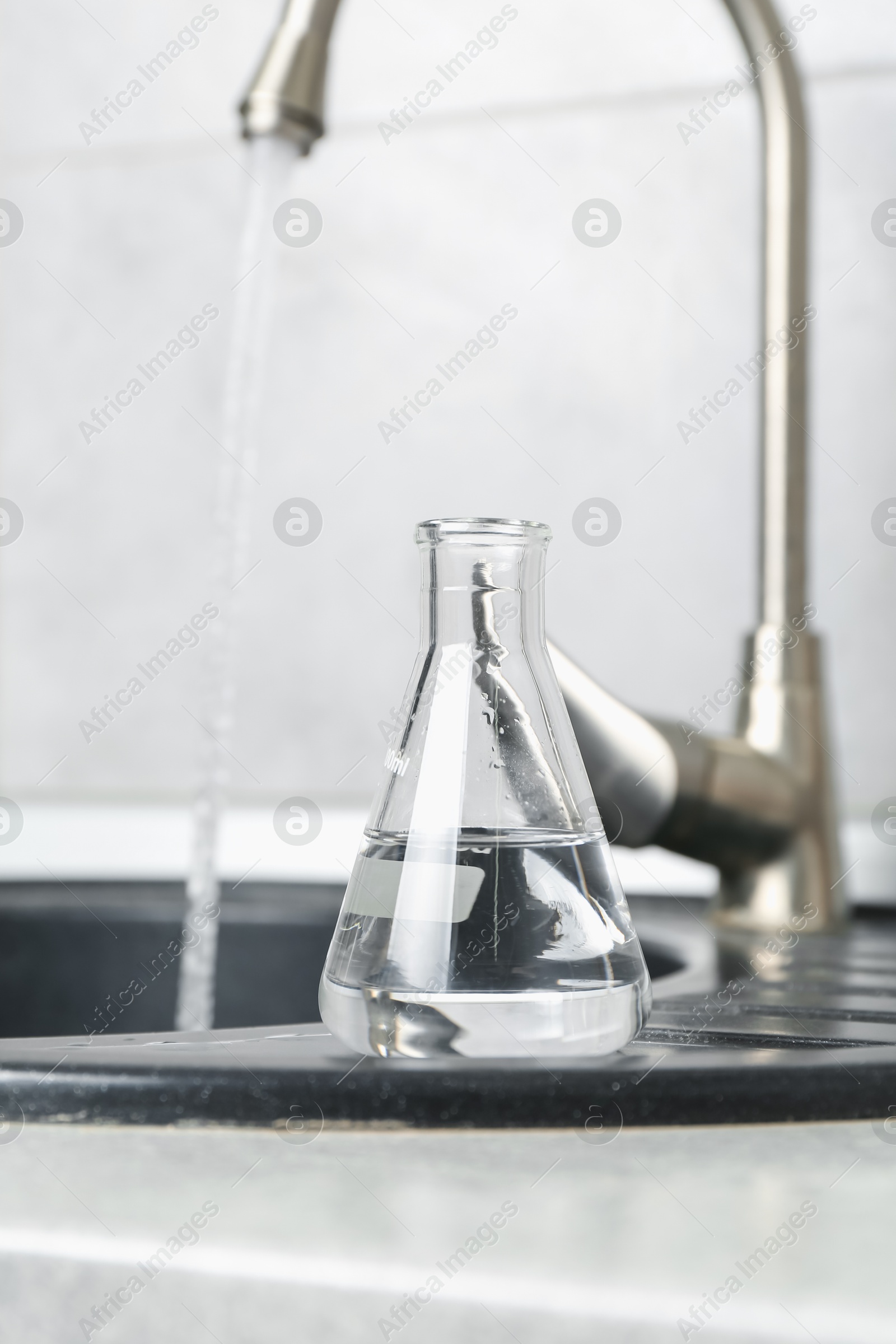 Flask with clean water near sink on counter in kitchen, closeup Photo of Flask with clean water near sink on counter in kitchen, closeup