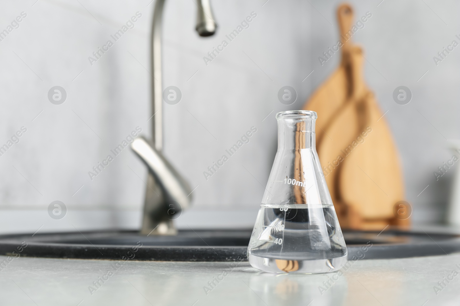 Flask with clean water near sink on counter in kitchen, closeup. Space for text Photo of Flask with clean water near sink on counter in kitchen, closeup. Space for text