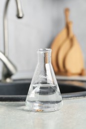Photo of Flask with clean water near sink on counter in kitchen, closeup