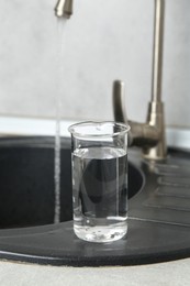 Photo of Beaker with clean water near sink on counter in kitchen, closeup