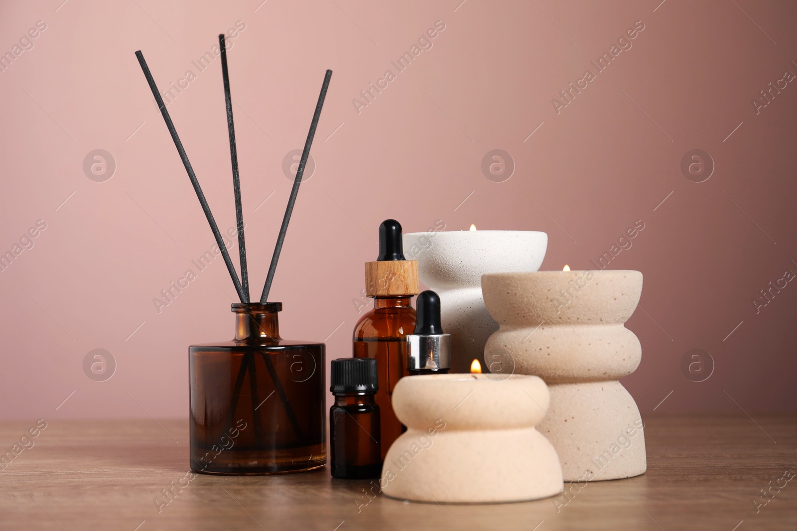 Spa composition with cosmetic products, burning candles and reed air freshener on wooden table against pink background, closeup Photo of Spa composition with cosmetic products, burning candles and reed air freshener on wooden table against pink background, closeup