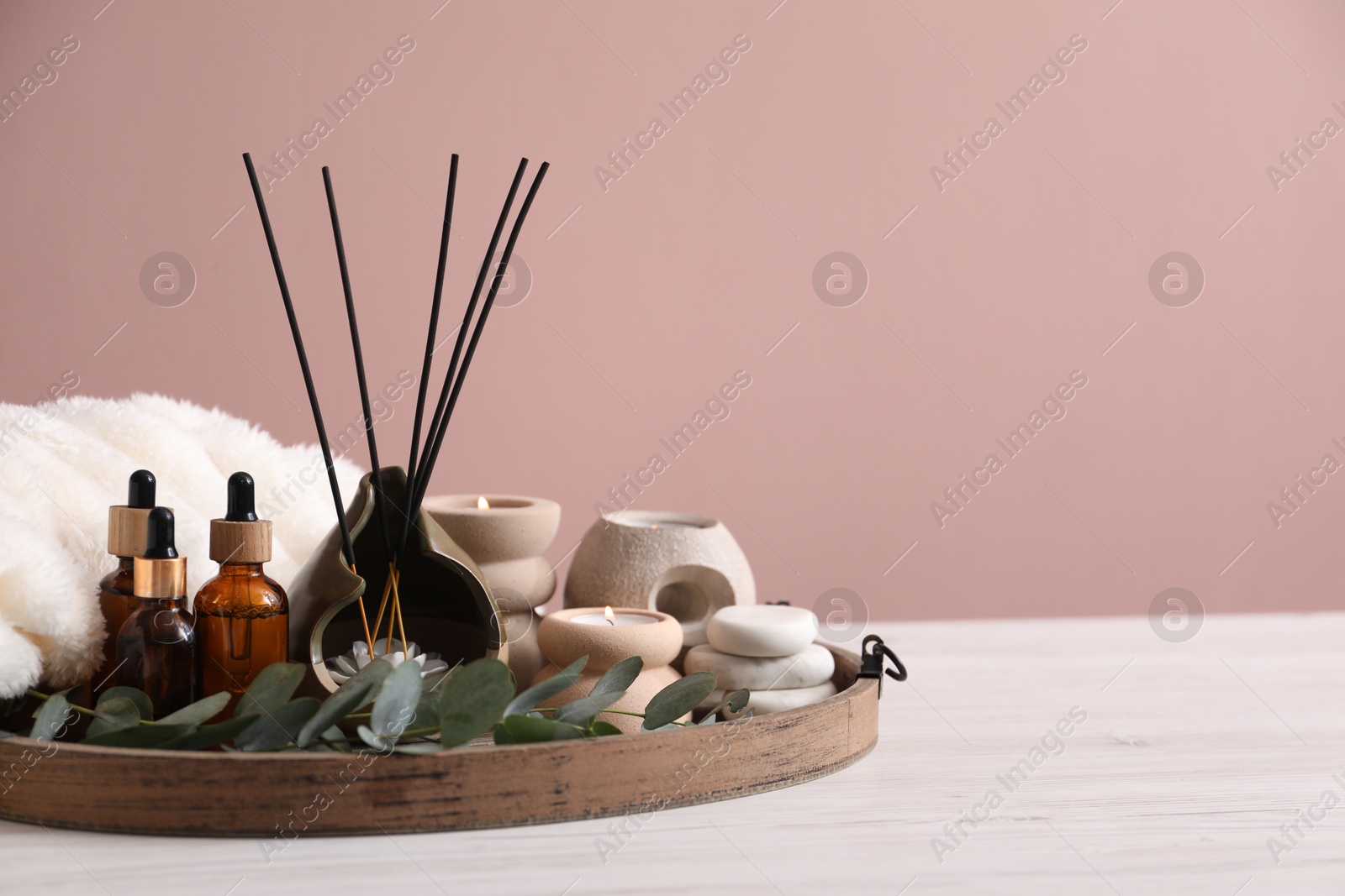 Spa composition of holder with incense sticks, burning candles and cosmetic products on white wooden table against pink background. Space for text Photo of Spa composition of holder with incense sticks, burning candles and cosmetic products on white wooden table against pink background. Space for text