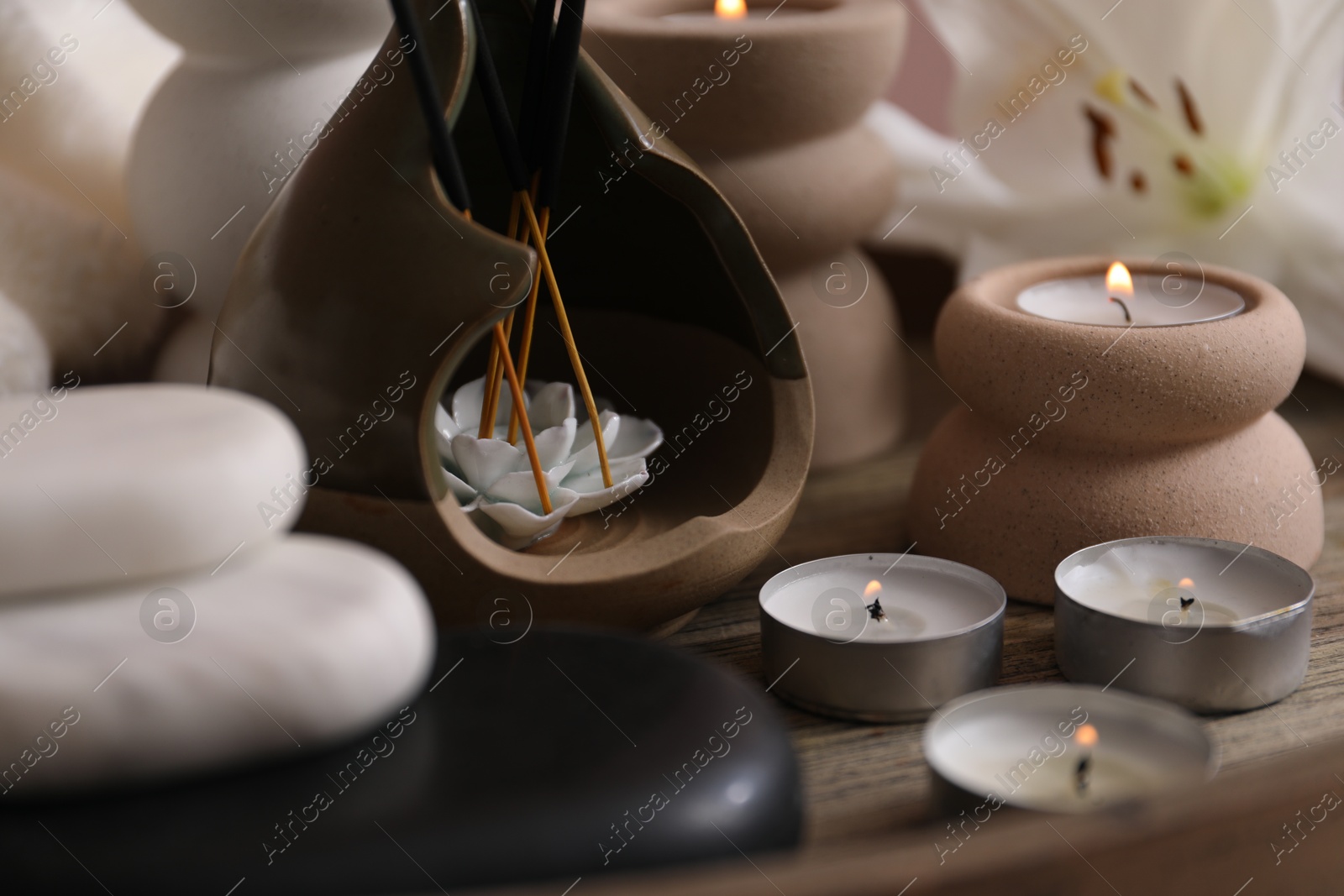 Holder with incense sticks, burning candles and spa stones on wooden tray, closeup Photo of Holder with incense sticks, burning candles and spa stones on wooden tray, closeup