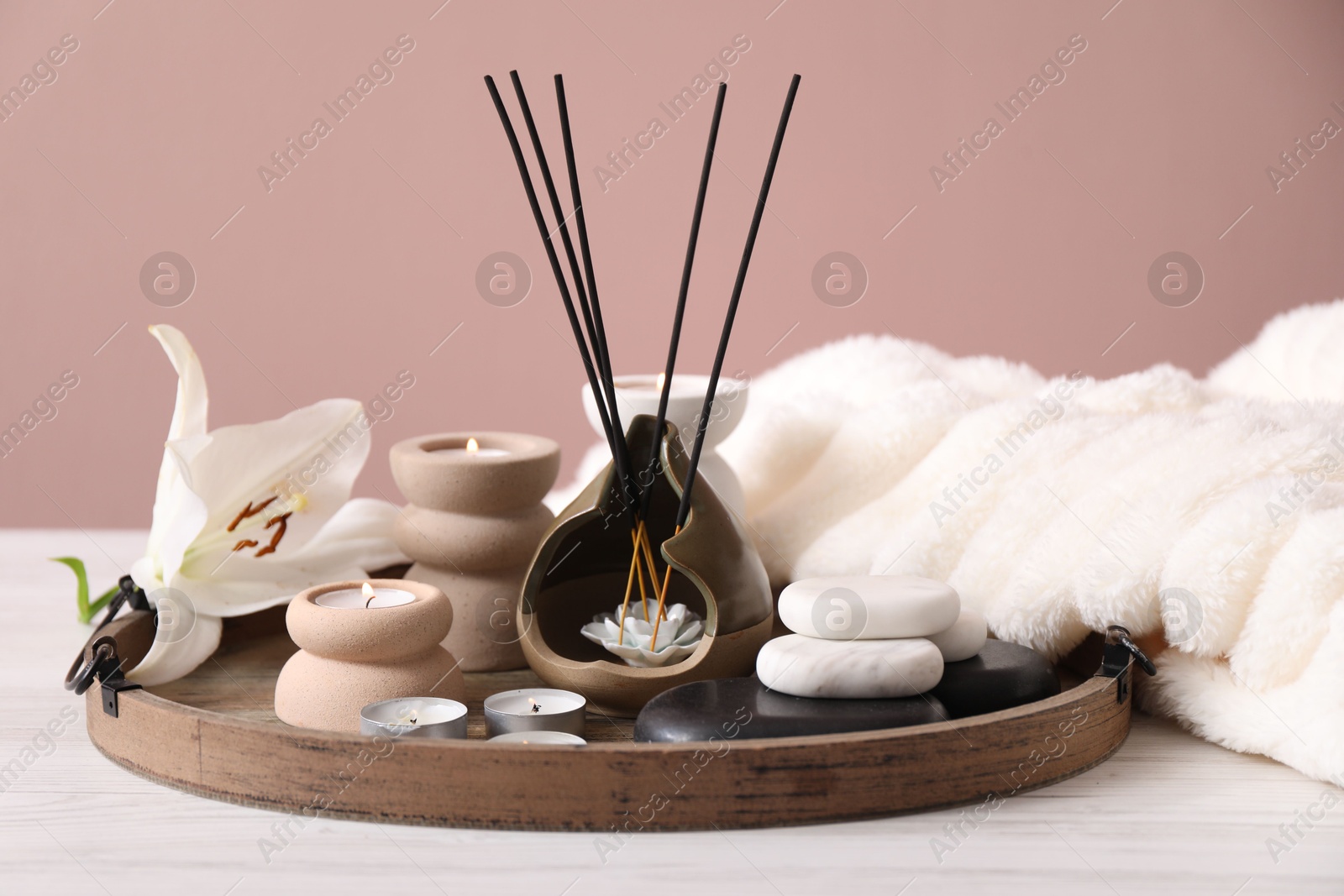 Composition with incense sticks, burning candles and spa stones on white wooden table against pink background, closeup Photo of Composition with incense sticks, burning candles and spa stones on white wooden table against pink background, closeup