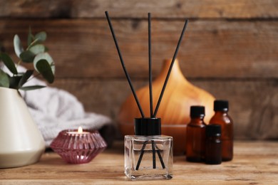 Photo of Spa composition with reed air freshener on wooden table, closeup