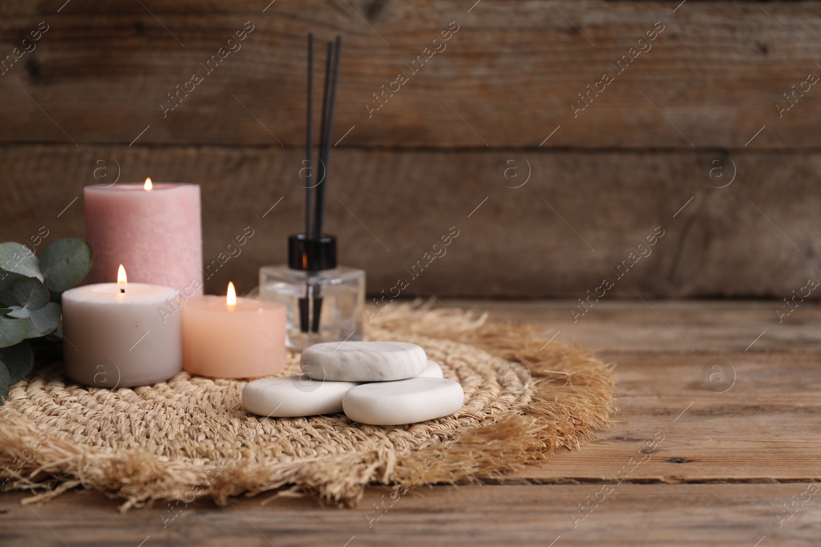 Composition with spa stones, reed air freshener and burning candles on wooden table, closeup. Space for text Photo of Composition with spa stones, reed air freshener and burning candles on wooden table, closeup. Space for text