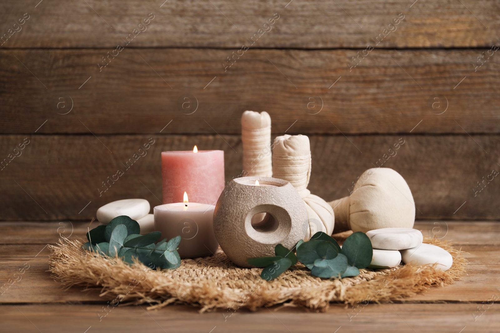 Composition with burning candles, spa stones and eucalyptus branches on wooden table, closeup Photo of Composition with burning candles, spa stones and eucalyptus branches on wooden table, closeup