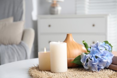 Photo of Spa composition with burning candles, aroma oil diffuser and flowers on white table indoors, closeup