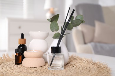 Photo of Spa composition with reed air freshener, burning candles and cosmetic products on white table indoors, closeup