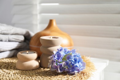 Photo of Spa composition with burning candles, aroma oil diffuser and flowers on white table indoors, closeup
