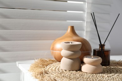 Photo of Spa composition with burning candles, aroma oil diffuser and reed air freshener on white table indoors, closeup
