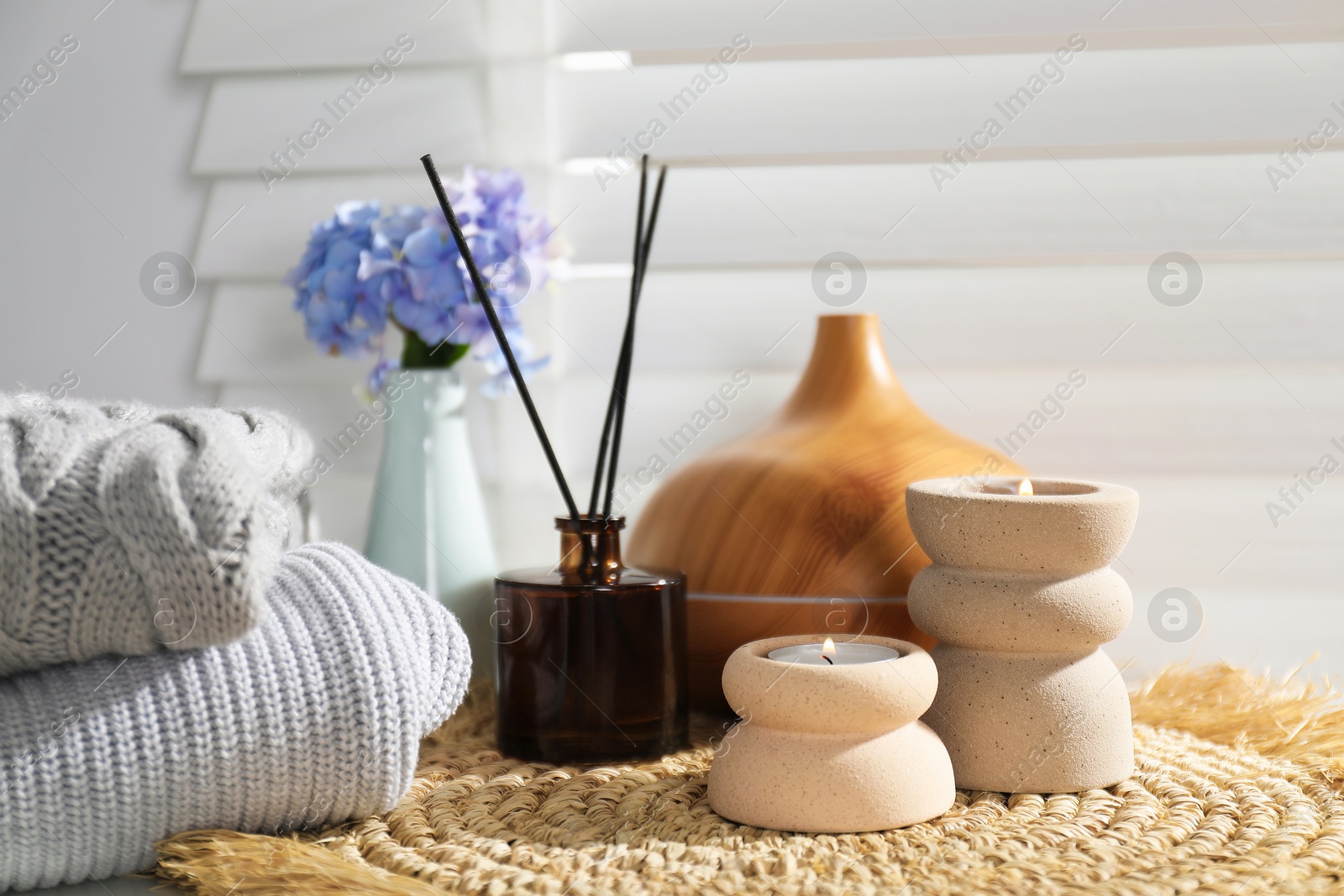Spa composition with burning candles, aroma oil diffuser and reed air freshener on wicker mat indoors, closeup Photo of Spa composition with burning candles, aroma oil diffuser and reed air freshener on wicker mat indoors, closeup