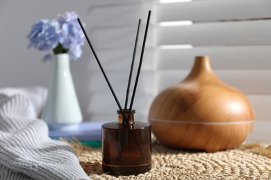 Photo of Spa composition with reed air freshener on wicker mat indoors, closeup