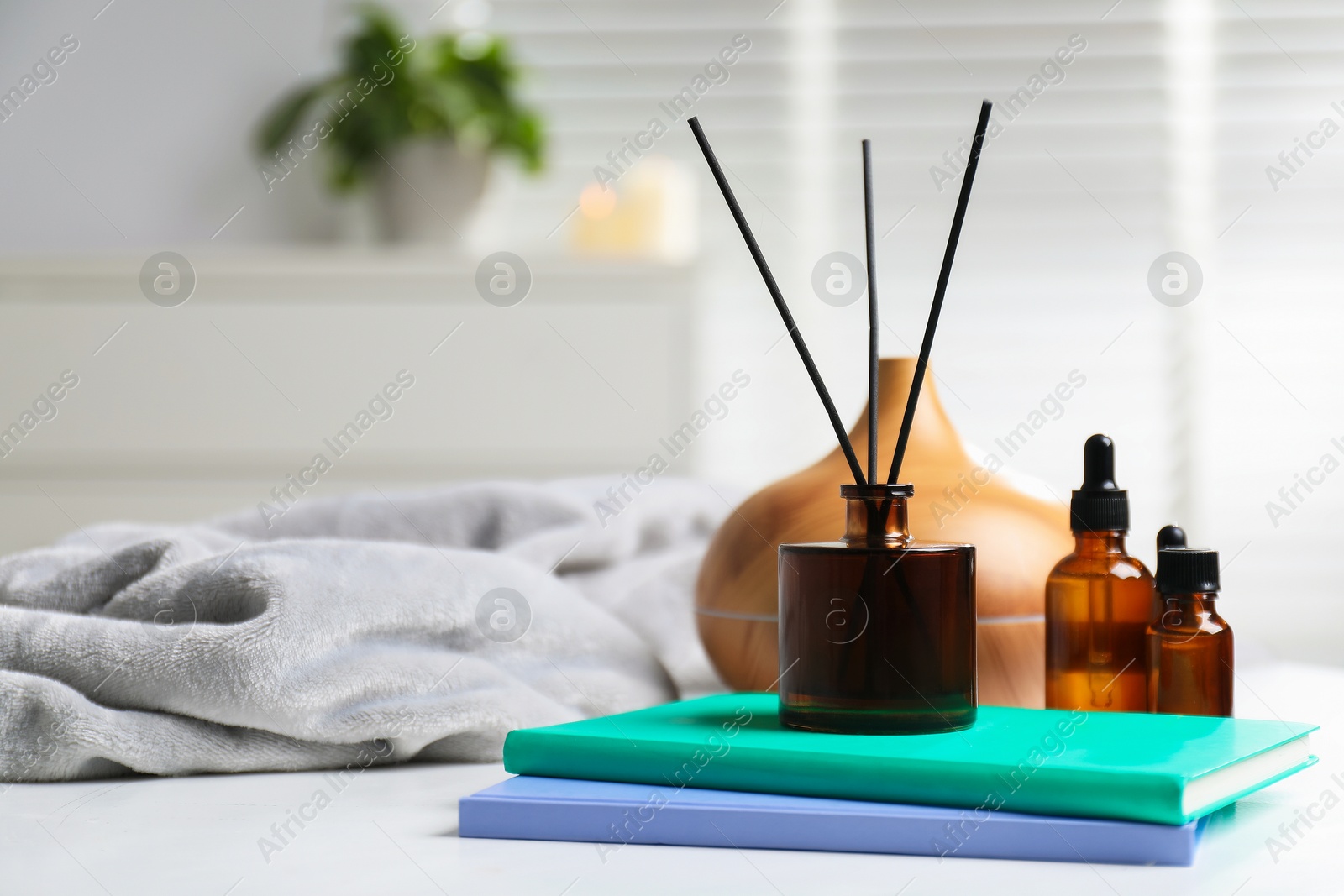 Spa composition with reed air freshener, cosmetic products and books on white table indoors, closeup Photo of Spa composition with reed air freshener, cosmetic products and books on white table indoors, closeup