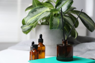 Photo of Spa composition with reed air freshener, cosmetic products and book on white table indoors, closeup