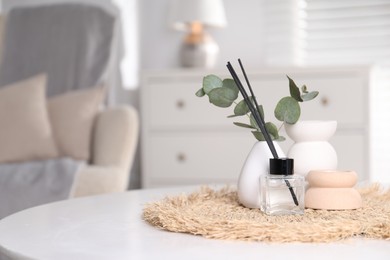 Photo of Spa composition with reed air freshener and eucalyptus branches on white table indoors. Space for text
