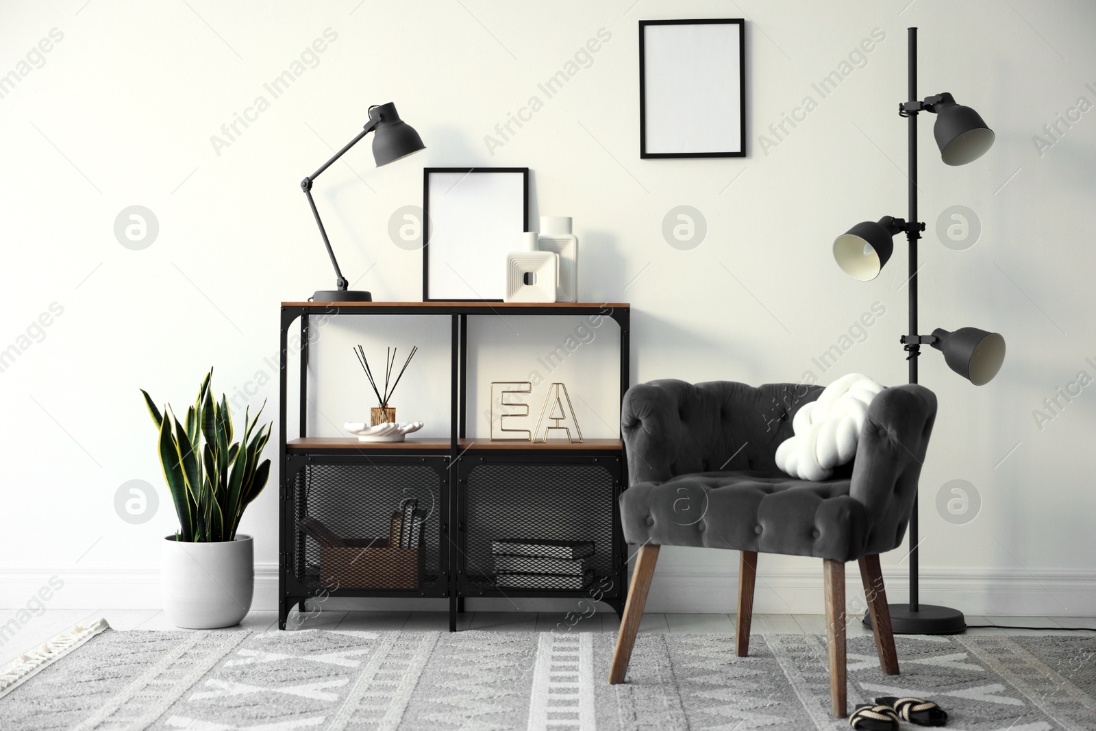 Stylish grey armchair, shelving unit and houseplants indoors. Interior design Photo of Stylish grey armchair, shelving unit and houseplants indoors. Interior design