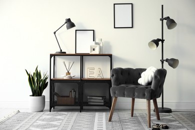 Photo of Stylish grey armchair, shelving unit and houseplants indoors. Interior design