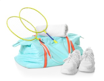 Photo of Stylish sports bag with badminton rackets, towel and sneakers isolated on white