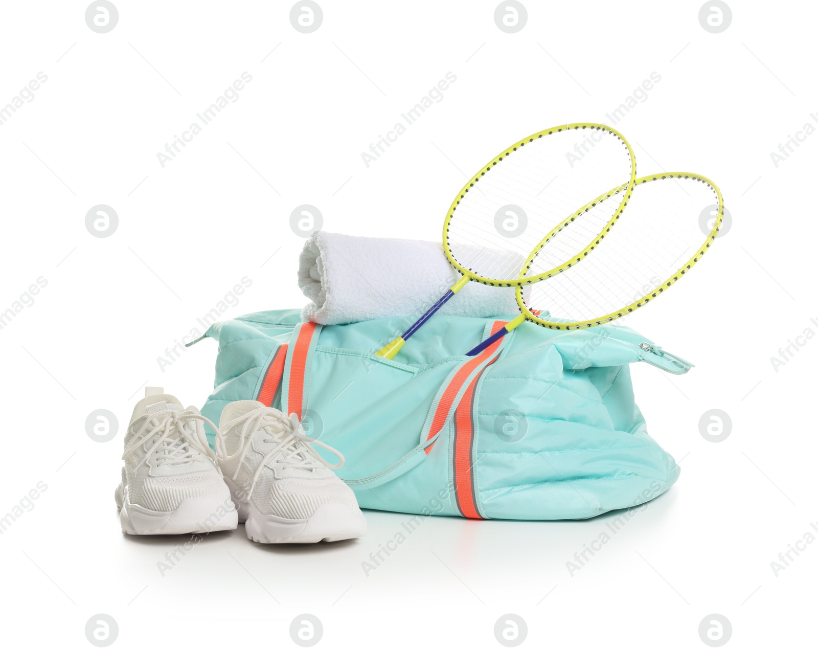 Photo of Stylish sports bag with badminton rackets, towel and sneakers isolated on white