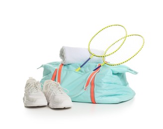 Photo of Stylish sports bag with badminton rackets, towel and sneakers isolated on white