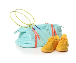 Photo of Stylish sports bag with badminton rackets and sneakers isolated on white
