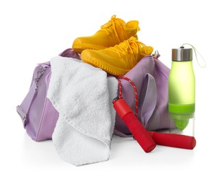 Photo of Stylish sports bag with skipping rope, bottle, towel and sneakers isolated on white